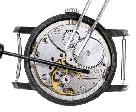 adjusting old mechanic wristwatch - above view of screwdriver and tweezers on open repaired watch isolated on white backgroundの写真素材