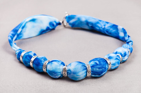textile necklace from blue painted silk balls and silver rings on gray backgroundの写真素材