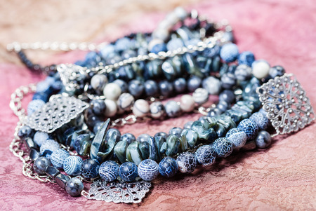 tangled gray blue agate necklace from natural gem stones (Dragon Veins Agate, shell, silk jasper, hematite, labradorite beads) on painted textile backgroundの写真素材