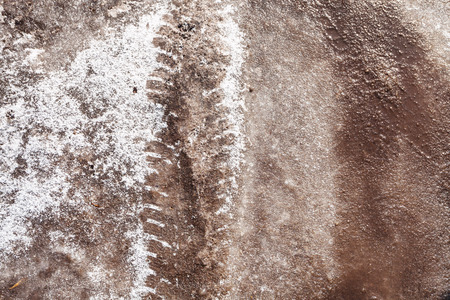 Tire tracks in frozen snow-covered road in springの写真素材