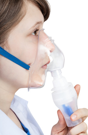 medical inhalation treatment - girl inhales with face mask of modern inhaler isolated on white backgroundの写真素材