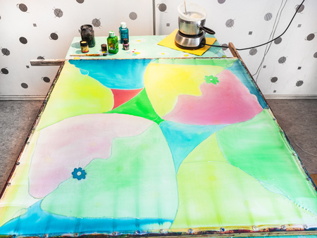 manufacturing steps of hot batik in the workshop - silk fabric with first layer of paintsの写真素材
