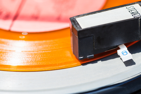 headshell of record-player on orange vinyl disc close upの写真素材