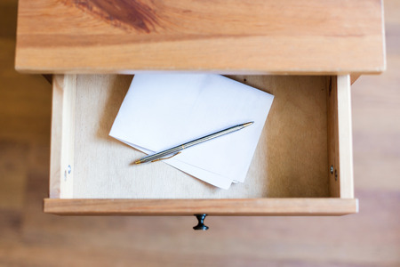 above view of folded sheet of paper and pen in open drawer of nightstandの写真素材