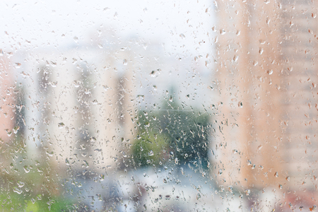 rainy weather in city - view of wet window glass of urban houseの写真素材