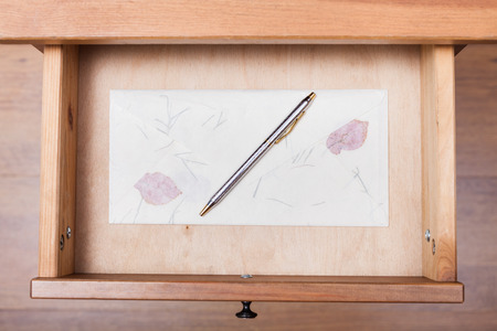 above view of ballpen on vintage envelope in open drawer of nightstandの写真素材