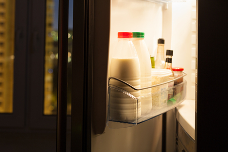 Open door of home fridge with dairy products in nightの写真素材