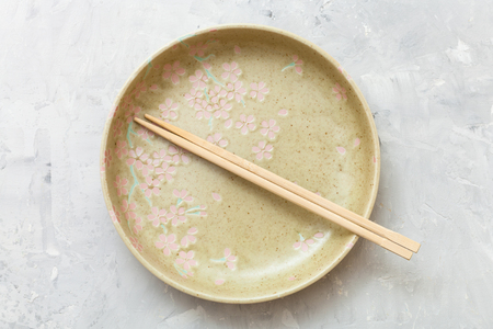 top view of one yellow green plate with chopsticks on gray concrete surfaceの写真素材