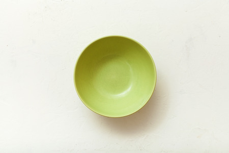 top view of green bowl on white plastering plateの写真素材