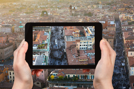 travel concept - tourist photographs street in Bologna city on tablet in Italy