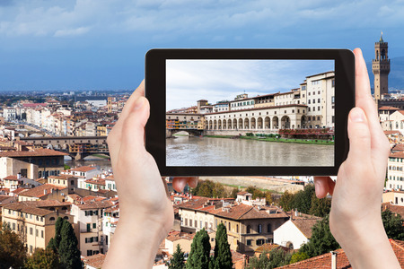 travel concept - tourist photographs vasari corridor from Arno River in Florence city on tablet in Italyの写真素材