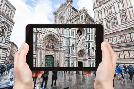travel concept - tourist photographs facade of Duomo Santa Maria del Fiore in Florence city on tablet in Italyの写真素材