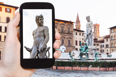 travel concept - tourist photographs sculpture of Neptune on piazza on signoria in Florence city on smartphone in Italyの写真素材