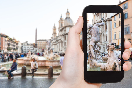 travel concept - tourist photographs sculptures of fountain on piazza Navona in Rome city on smartphone in Italyの写真素材