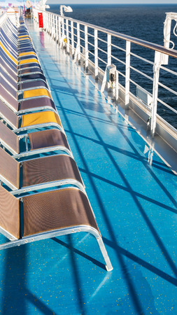 line of empty sunbathing chairs on deck of cruise linerの写真素材