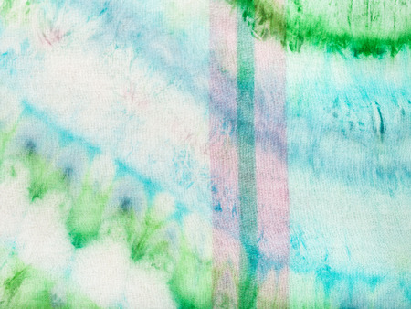 textile background - abstract blue and green pattern with pink stripe dyed on fabric in nodular batik technique close upの写真素材