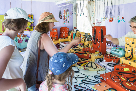 PIAZZA ARMERINA, ITALY - JUNE 29, 2011: tourists choose necklaces from lava in souvenir shop in Sicily. Lava decorations are popular in Sicily, there is a lot of ornamental material from Etna volcanoのeditorial素材