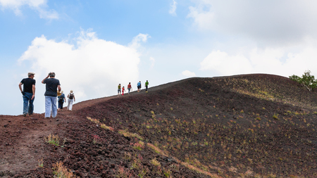 ETNA, ITALY - JULY 1, 2011 - tourists walk on ridge between old craters of Etna volcano. Mount Etna is active volcano on the east coast of Sicily, the tallest active volcano in Europeのeditorial素材