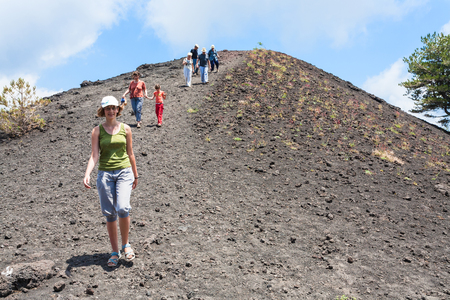 ETNA, ITALY - JULY 1, 2011 - tourists walk on ridge between old crater of Etna mount. Mount Etna is active volcano on the east coast of Sicily, the tallest active volcano in Europeのeditorial素材