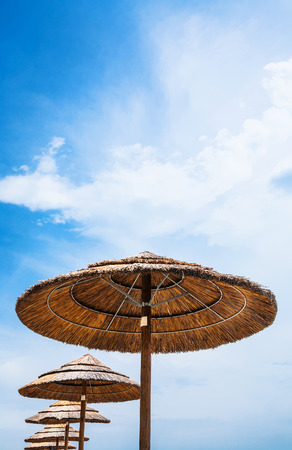Italy - straw parasols and blue sky on San Marco beach in Sicilyの写真素材