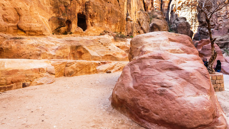 PETRA, JORDAN - FEBRUARY 21, 2012: tourists near caves in Al Siq gorge to ancient Petra town in winter. Rock-cut town Petra was established about 312 BC as the capital city of the Arab Nabataeanのeditorial素材