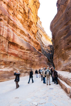 PETRA, JORDAN - FEBRUARY 21, 2012: tourists in Al Siq pass to ancient Petra town in winter. Rock-cut town Petra was established about 312 BC as the capital city of the Arab Nabataeanのeditorial素材