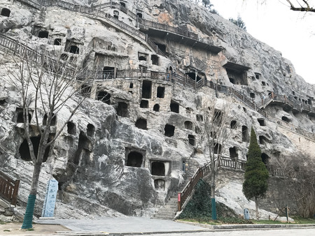 LUOYANG, CHINA - MARCH 20, 2017: carved caves and houses in Chinese Buddhist monument Longmen Grottoes (Longmen Caves). The complex was inscribed upon the UNESCO World Heritage List in 2000のeditorial素材