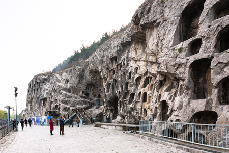 LUOYANG, CHINA - MARCH 20, 2017: people near caves in slope of West Hill of Chinese Buddhist monument Longmen Grottoes. The complex was inscribed upon the UNESCO World Heritage List in 2000のeditorial素材