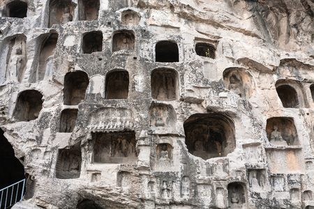 LUOYANG, CHINA - MARCH 20, 2017: carved figures and caves in wall of West Hill of Chinese Buddhist monument Longmen Grottoes. The complex was inscribed upon the UNESCO World Heritage List in 2000のeditorial素材