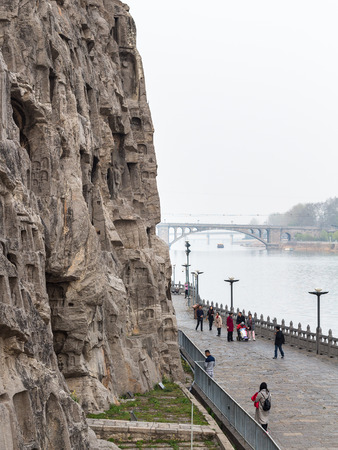 LUOYANG, CHINA - MARCH 20, 2017: view of people on waterfront and Bridge in Chinese Buddhist monument Longmen Grottoes. The complex was inscribed upon the UNESCO World Heritage List in 2000のeditorial素材