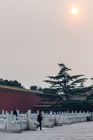 BEIJING, CHINA - MARCH 19, 2017: tourists near wall of gate in Imperial Ancestral Hall public park in Beijing Imperial city under sun in brown from smog sky in springのeditorial素材