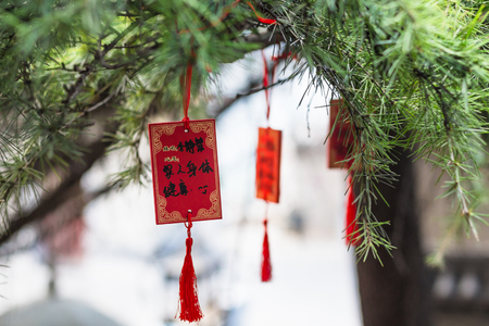LUOYANG, CHINA - MARCH 20, 2017: red plates on tree near temple of Chinese Buddhist monument Longmen Grottoes in spring. The complex was inscribed upon the UNESCO World Heritage List in 2000のeditorial素材