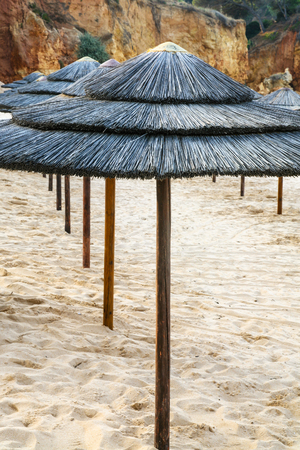 Travel to Algarve Portugal - straw parasols on beach Praia Falesia near Albufeira cityの写真素材