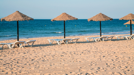 Travel to Algarve Portugal - empty loungers on beach praia da rocha baixinha nascente in vilamoura area near Albufeira city in eveningの写真素材