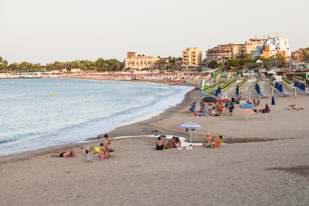 GIARDINI NAXOS, ITALY - JULY 1, 2017: people on city beach in Giardini-Naxos town in summer evening. Giardini Naxos is seaside resort on Ionian Sea coast since the 1970sのeditorial素材
