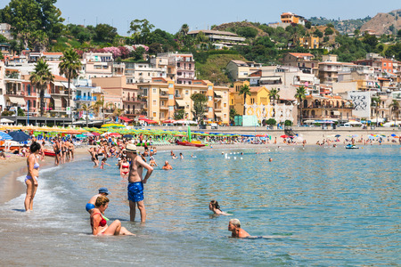GIARDINI NAXOS, ITALY - JUNE 30, 2017: tourists on urban beach in Giardini-Naxos city in summer. Giardini Naxos is seaside resort on Ionian Sea coast since the 1970sのeditorial素材