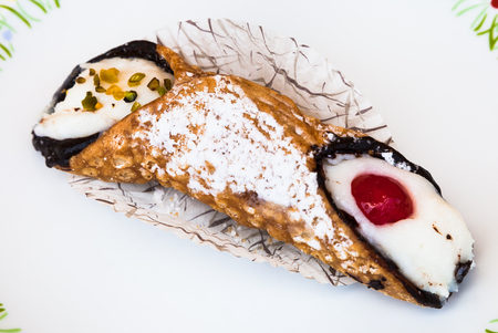 typical sicilian pastry Cannoli sprinkled with confectioner's sugar omn white plateの写真素材