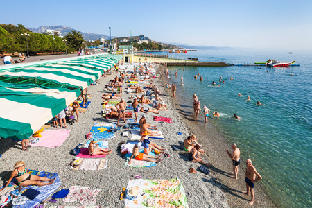 ALUSHTA, CRIMEA - SEPTEMBER 21, 2017: tourists on urban pebble beach on coast of Black Sea in Alushta city. Alushta is seaside resort town on southern coast of the Crimean peninsula.のeditorial素材