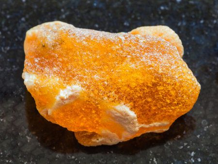 macro shooting of natural mineral rock specimen - raw baltic Amber stone on dark granite background...