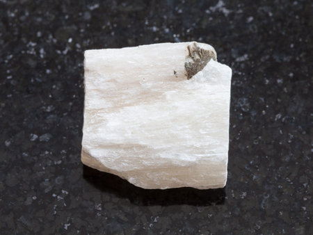 macro shooting of natural mineral rock specimen - rough Gypsum stone on dark granite background