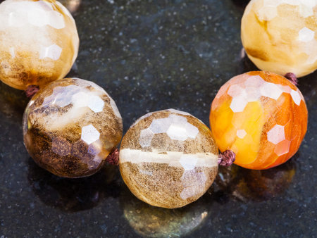 macro shooting of natural mineral rock specimen - necklace from various smoky quartz gemstones on dark granite backgroundの写真素材