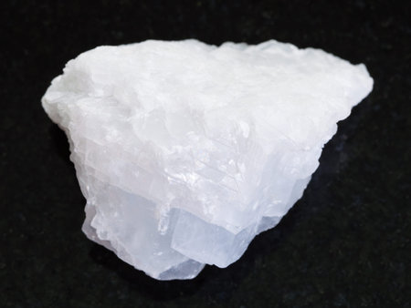 macro shooting of natural mineral rock specimen - raw crystalline Magnesite stone on dark granite...