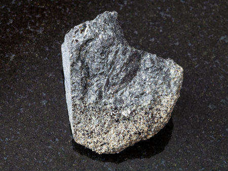 macro shooting of natural mineral rock specimen - raw peridotite stone on dark granite background...