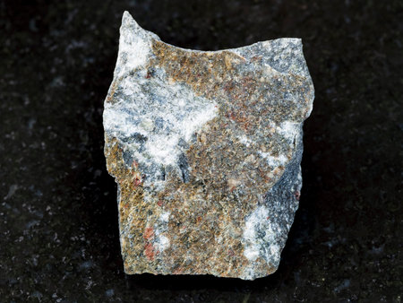 macro shooting of natural mineral rock specimen - surface of rough Andesite stone on dark granite...