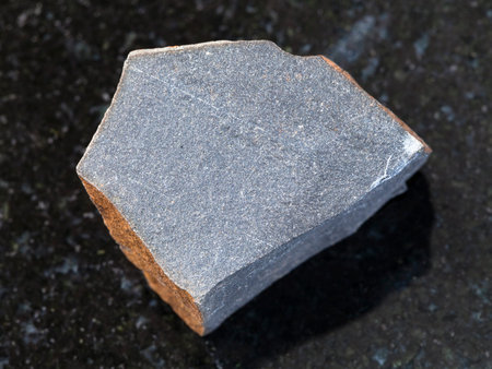 macro shooting of natural mineral rock specimen - rough hyalobasalt (tachylite) stone on dark...