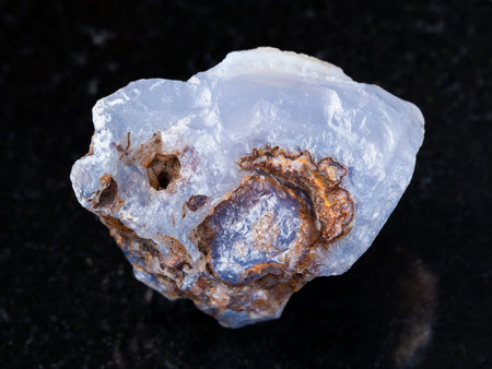 macro shooting of natural mineral rock specimen - raw crystal of blue Chalcedony gemstone on dark...