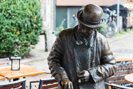 BREMEN, GERMANY - SEPTEMBER 16, 2017: bronze figure of Heini Holtenbeen, one of Bremen's most eccentric characters, in outdoor cafe in Schnoor quarter in Bremen city in rain.のeditorial素材