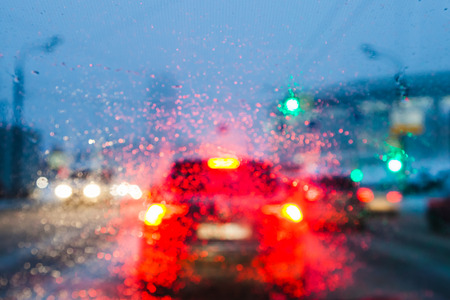 driving in night snowfall in Moscow - blurred background with view through melting snow on car windshield in winter eveningの写真素材