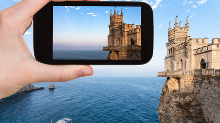 travel concept - tourist photographs Swallow's Nest castle over Black Sea on Crimean Southern Coast...