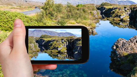 travel concept - tourist photographs Silfra fissure in rift valley of Thingvellir national park in Iceland in september on smartphoneの写真素材